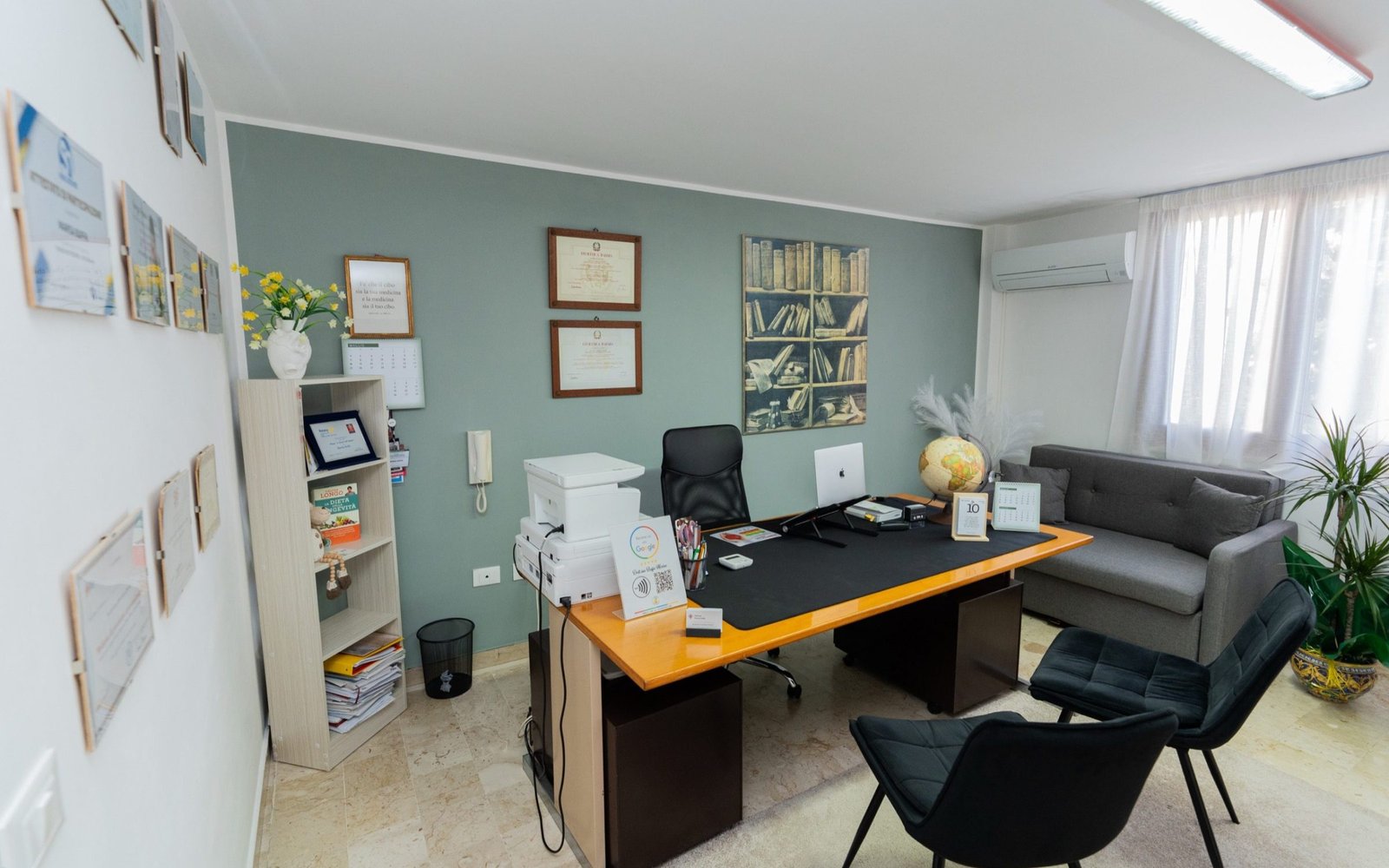 La sala visite dello studio: scrivania, poltrone e diplomi alle pareti